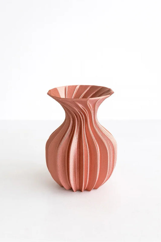 Sculptural pink vase with curved modern design isolated on white background.