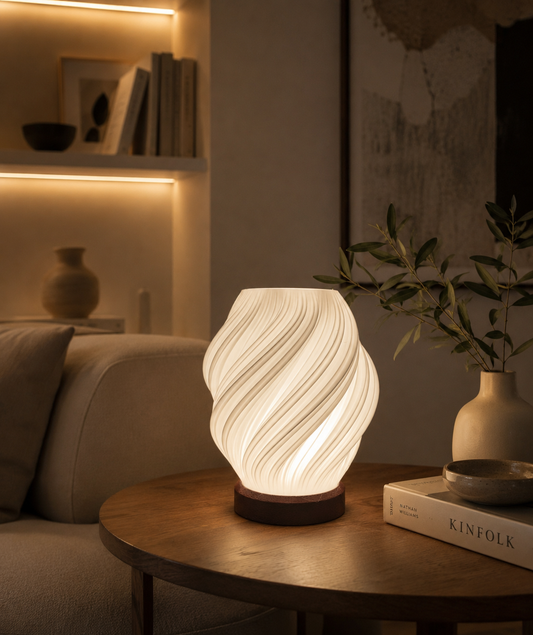 Lampada Ondea LED in PETG accesa su tavolino con luce calda e design fluido moderno