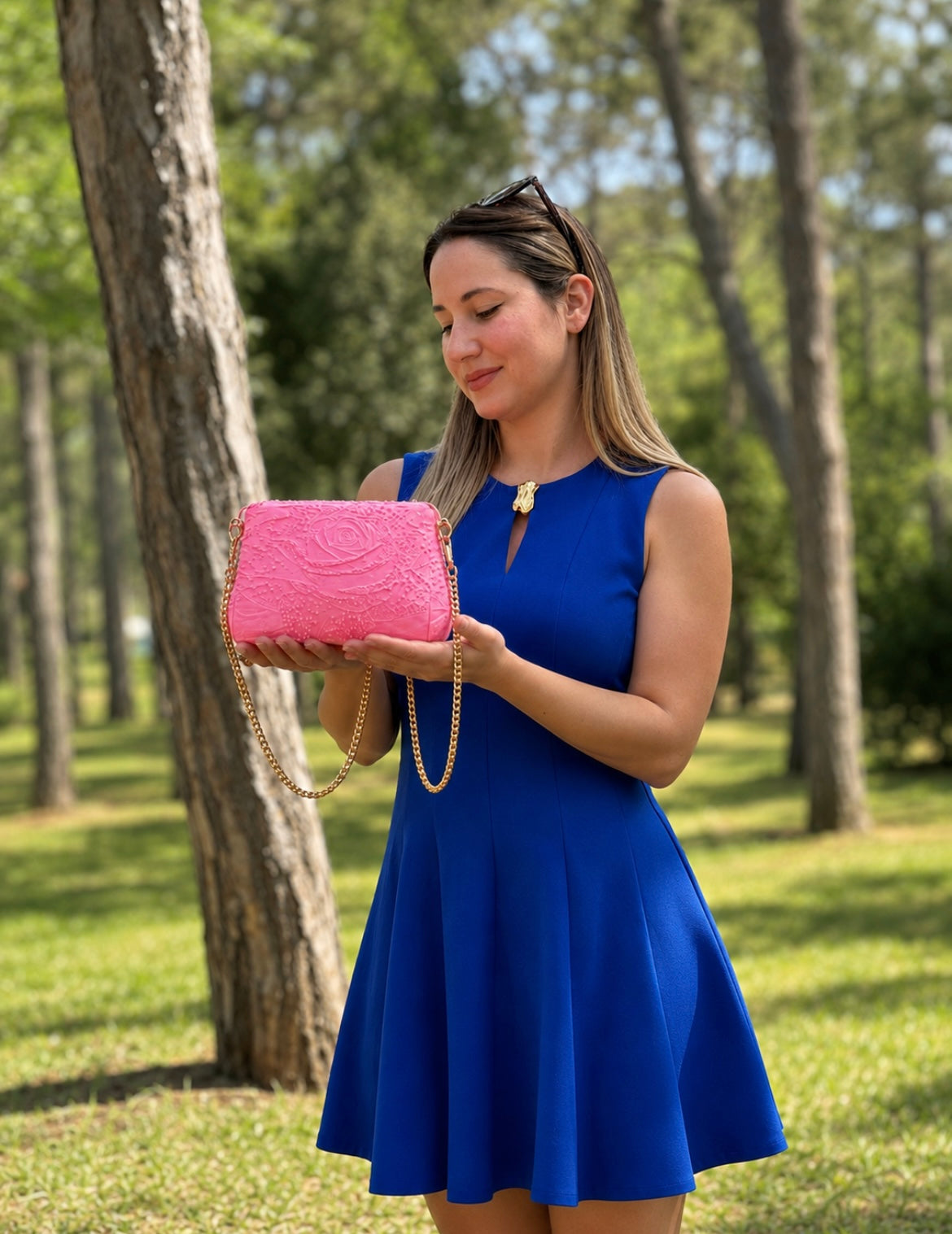 Elegant woman presenting a luxury pink designer handbag with embossed floral texture and gold chain strap. Premium 3D printed shoulder bag, modern fashion accessory, stylish women's purse, luxury gift idea, contemporary handcrafted design and exclusive lifestyle fashion.
