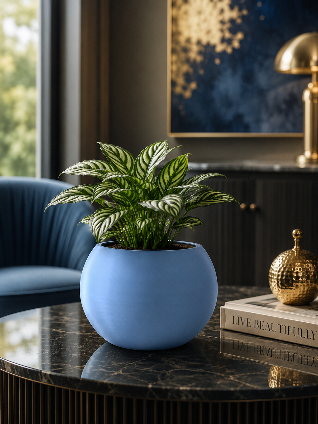 Premium blue decorative planter with an elegant tropical indoor plant displayed on a black marble table in a luxury contemporary living room. Modern home decoration, designer flower pot, 3D printed in Italy.