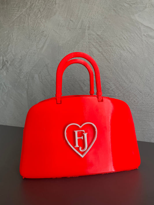 Red designer-inspired popcorn holder bag used in a movie theater, perfect for snacks, candy storage, cinema nights and modern home decor.