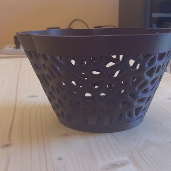 Cesto decorativo geometrico nero su sfondo colorato moderno che ne valorizza il design traforato.