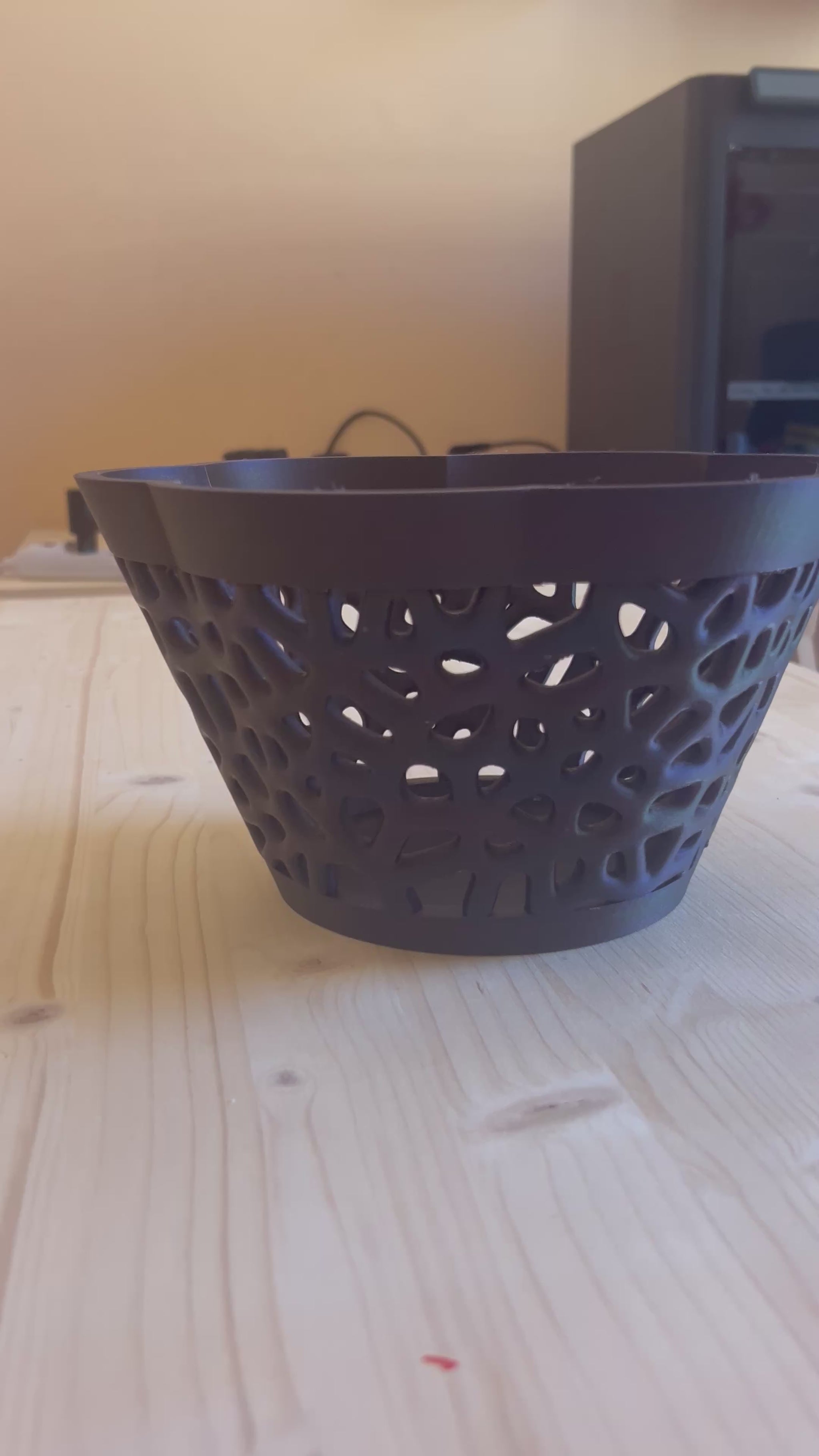 Cesto decorativo geometrico nero su sfondo colorato moderno che ne valorizza il design traforato.