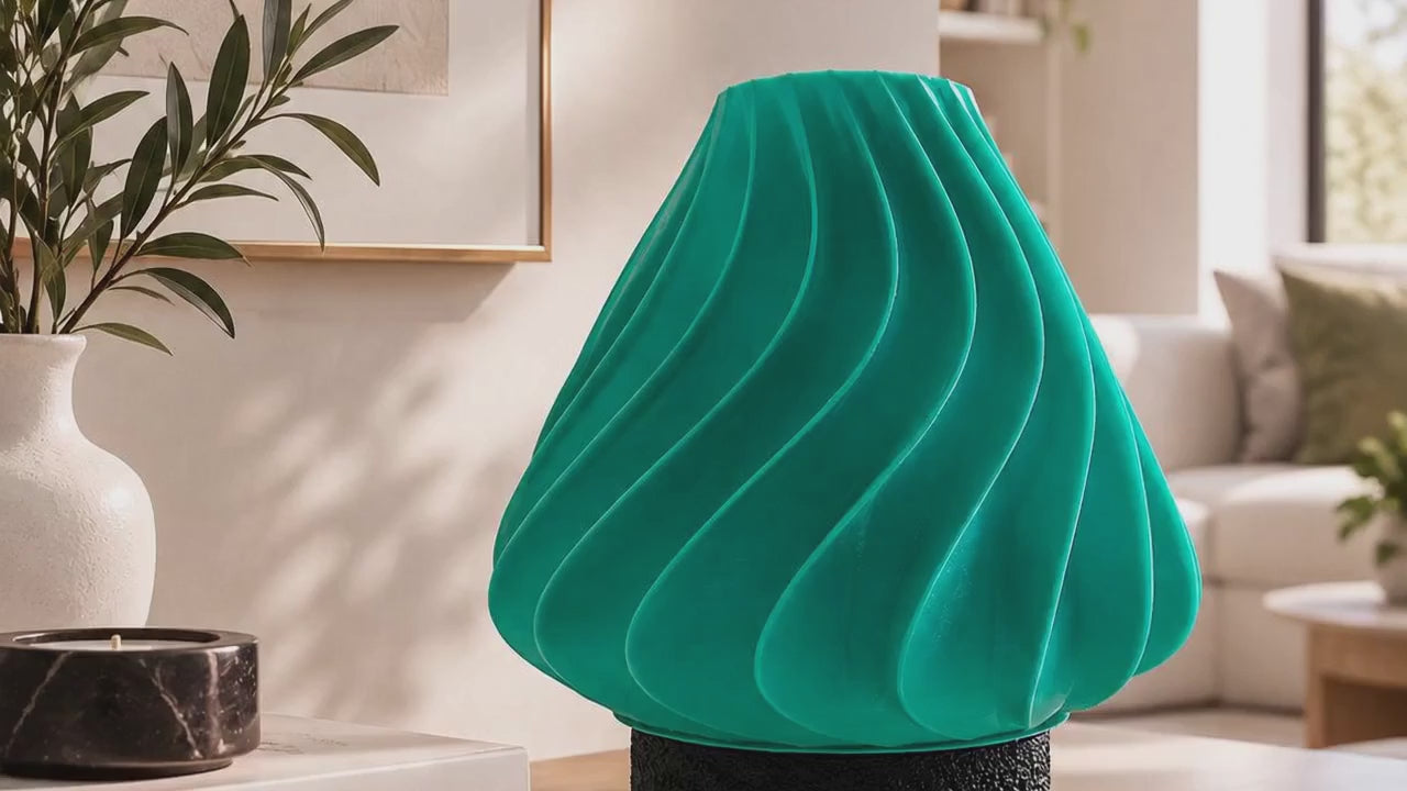 Discover a sculptural table lamp designed to become a statement piece in modern interiors. Its flowing wave-inspired form, turquoise finish and geometric black base combine contemporary design with atmospheric ambient lighting.
